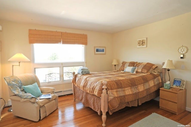 bedroom featuring hardwood / wood-style floors and a baseboard heating unit