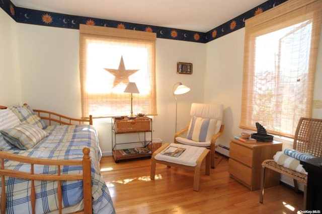 bedroom with wood-type flooring and a baseboard heating unit