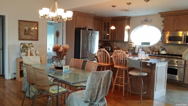 kitchen with hardwood / wood-style floors, decorative backsplash, appliances with stainless steel finishes, a kitchen island, and a chandelier