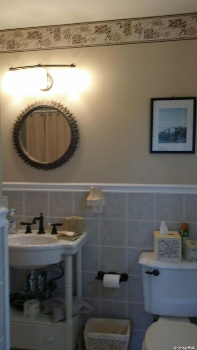 bathroom featuring toilet and tile walls