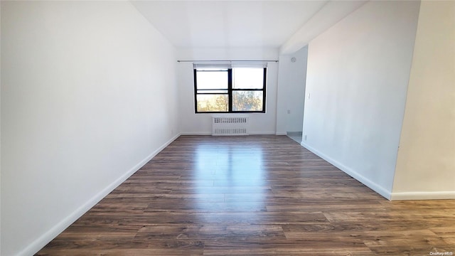 empty room with radiator heating unit and dark wood-type flooring