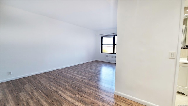 empty room featuring hardwood / wood-style floors and radiator heating unit