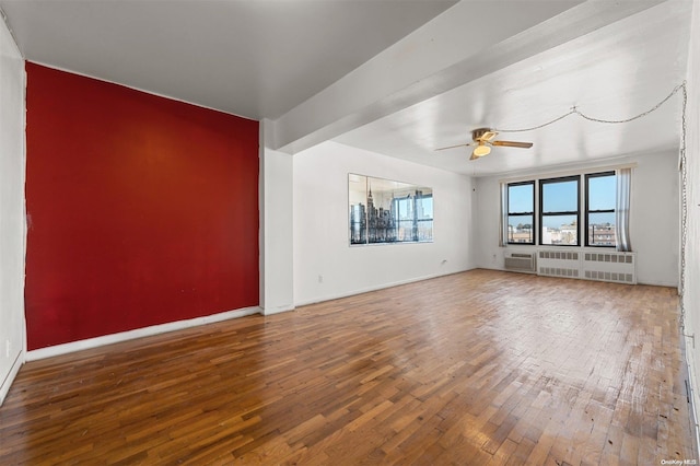 unfurnished living room featuring hardwood / wood-style flooring, ceiling fan, and radiator heating unit