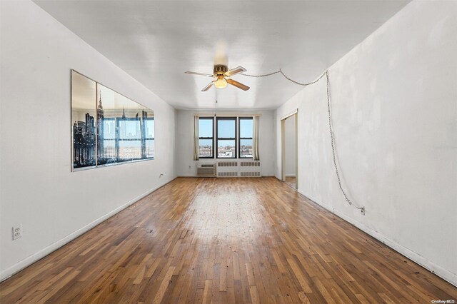 unfurnished room with ceiling fan, radiator heating unit, and hardwood / wood-style flooring