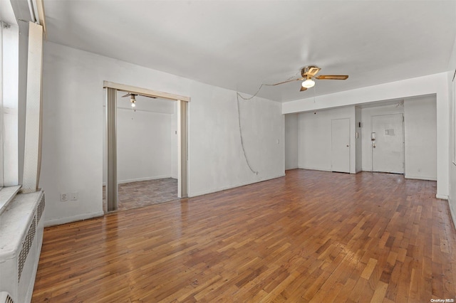 interior space with radiator heating unit, ceiling fan, and dark wood-type flooring