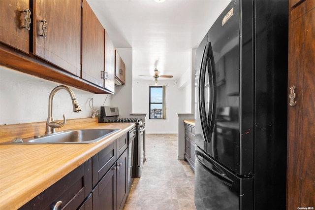 kitchen with black refrigerator, stainless steel gas stove, ceiling fan, and sink