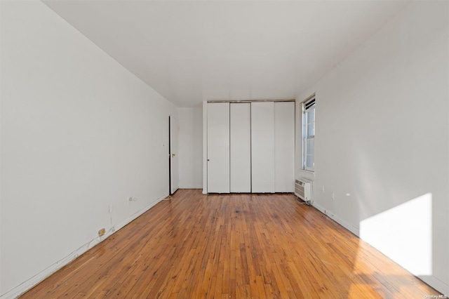 unfurnished bedroom featuring light wood-type flooring and a wall unit AC