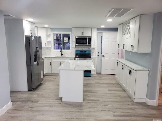 kitchen with white cabinetry, sink, black stove, refrigerator with ice dispenser, and a kitchen island