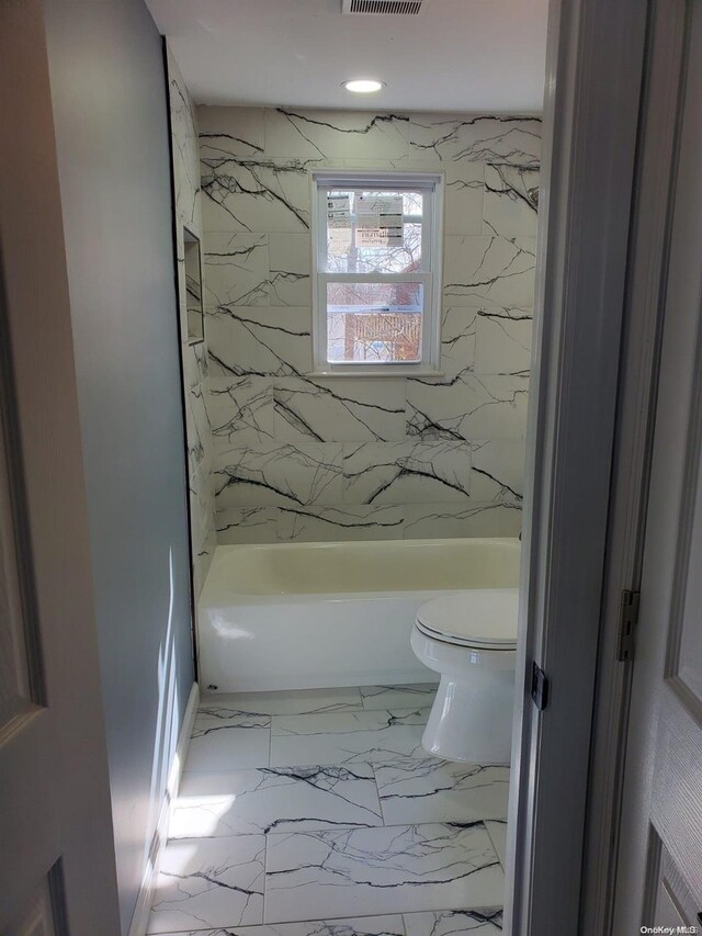 bathroom featuring tiled shower / bath combo and toilet