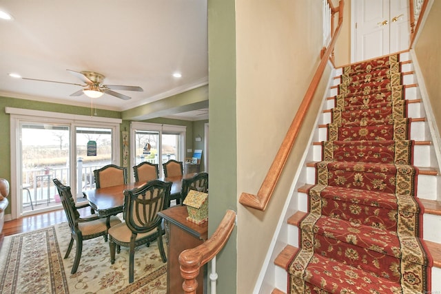 staircase with ceiling fan, wood-type flooring, and ornamental molding