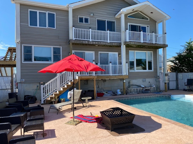 rear view of house featuring a fire pit, a patio area, a balcony, and a fenced in pool