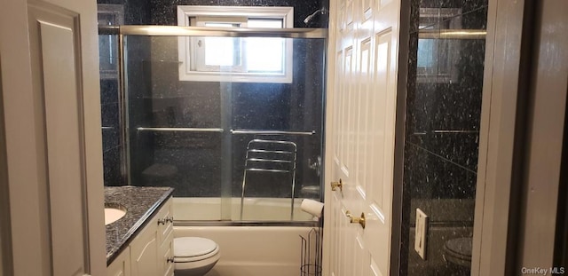 full bathroom with vanity, bath / shower combo with glass door, and toilet