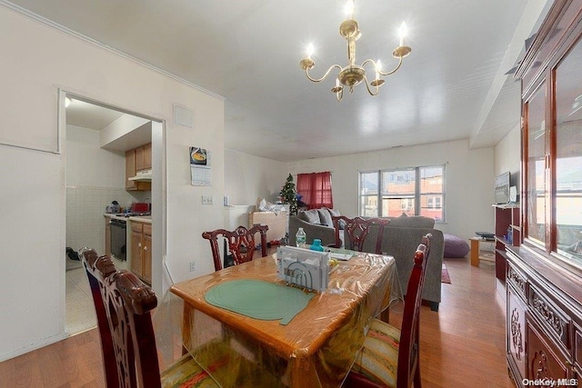 dining space featuring hardwood / wood-style flooring, tile walls, and a notable chandelier