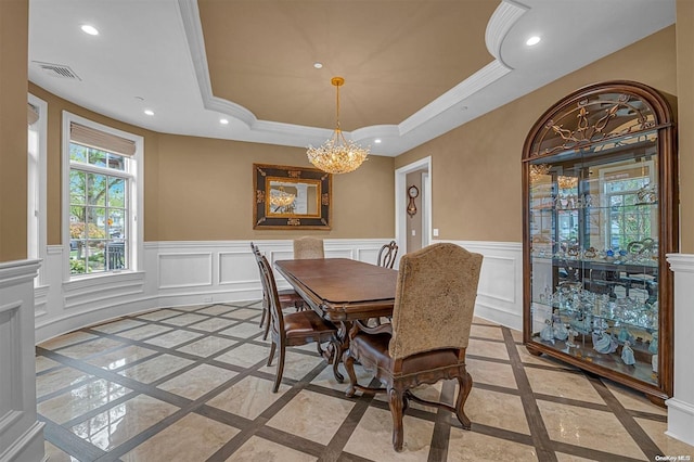 dining space with a raised ceiling, crown molding, and a notable chandelier