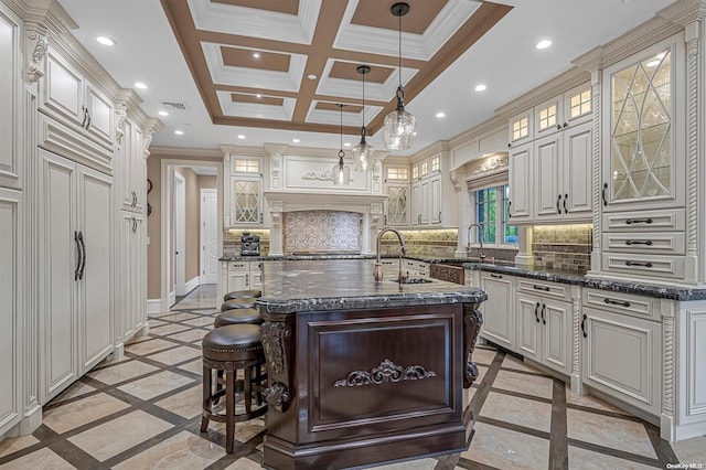 kitchen with a kitchen breakfast bar, decorative backsplash, an island with sink, and hanging light fixtures