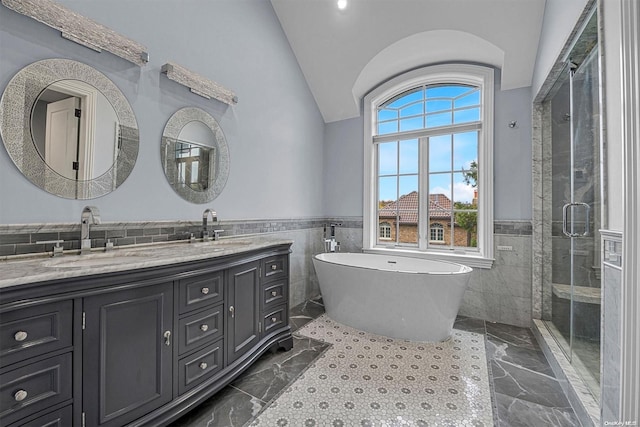 bathroom with separate shower and tub, tile walls, vanity, and vaulted ceiling