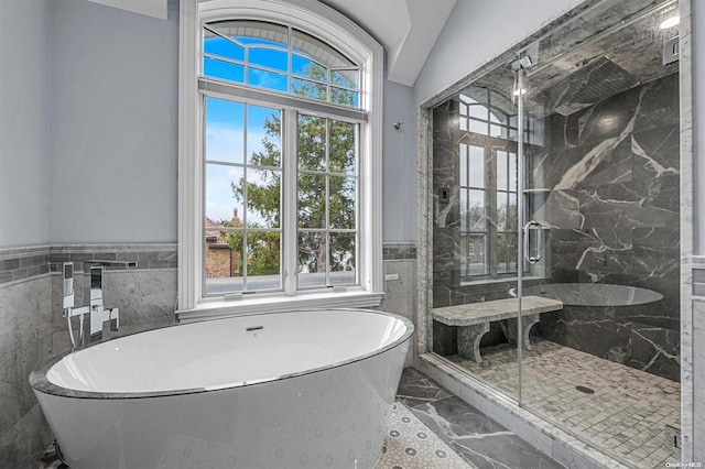 bathroom with tile walls, a shower with shower door, and vaulted ceiling