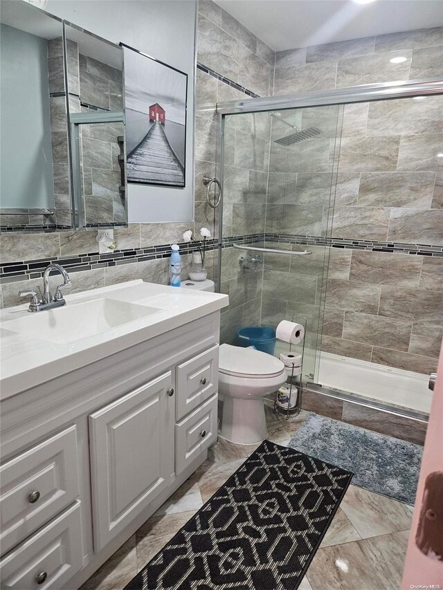 bathroom featuring vanity, a shower with shower door, tile walls, and toilet