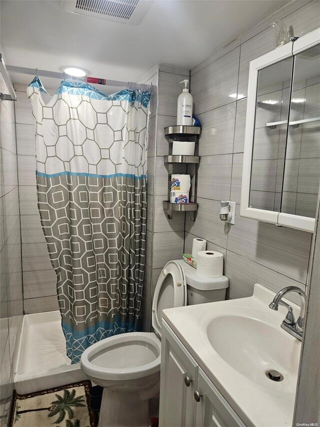 bathroom with toilet, vanity, tile walls, and a shower with shower curtain