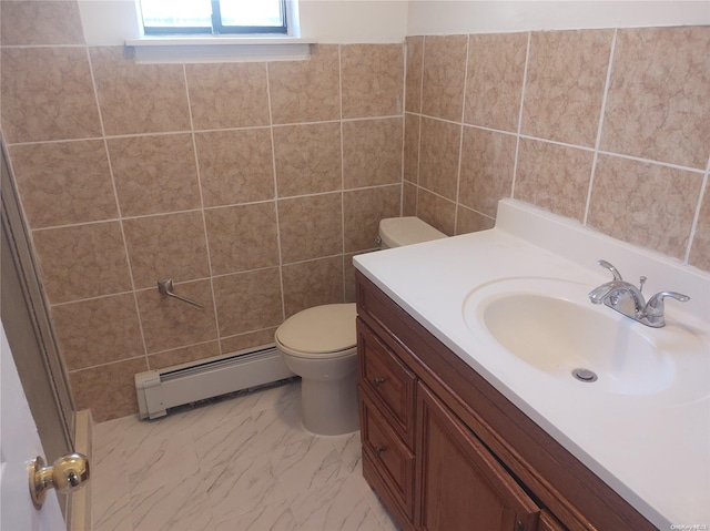 bathroom featuring vanity, toilet, baseboard heating, and tile walls