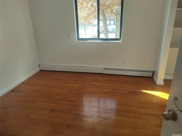 unfurnished room featuring wood-type flooring and a baseboard radiator