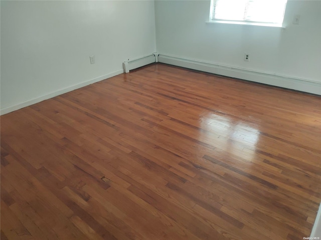 spare room with dark hardwood / wood-style flooring and baseboard heating