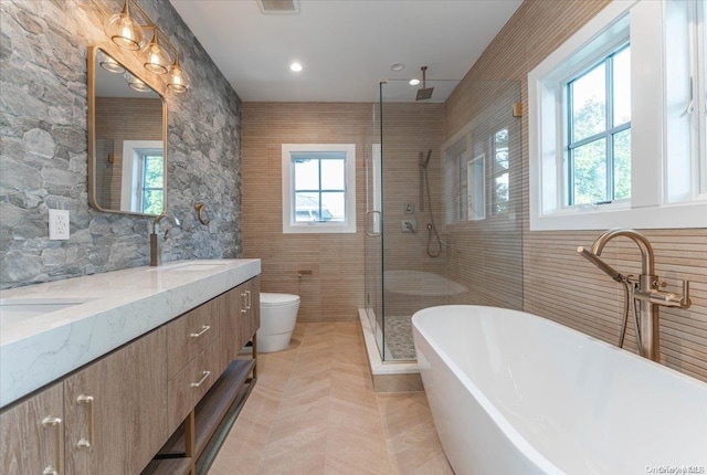 full bathroom with toilet, shower with separate bathtub, vanity, and tile walls