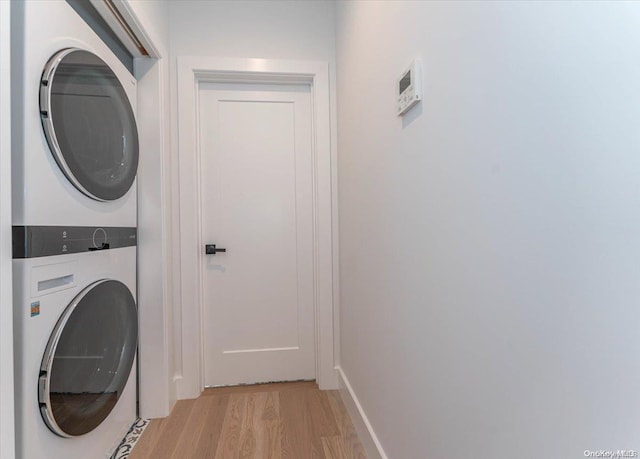 laundry room with light hardwood / wood-style floors and stacked washer and dryer