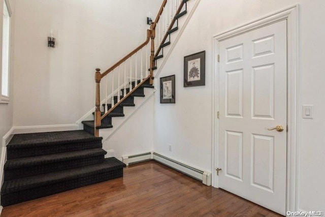 stairway featuring baseboard heating and wood-type flooring