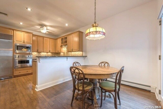 dining room with ceiling fan, dark hardwood / wood-style flooring, and a baseboard heating unit