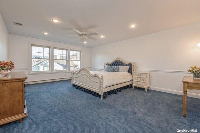 bedroom with dark colored carpet, ceiling fan, and a baseboard heating unit