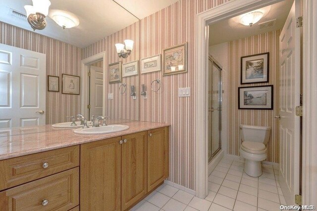 bathroom featuring an inviting chandelier, walk in shower, tile patterned floors, toilet, and vanity