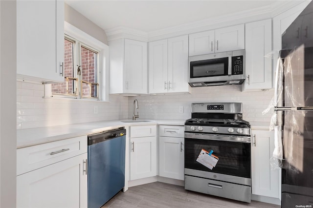 kitchen with white cabinets, light wood-type flooring, stainless steel appliances, and sink