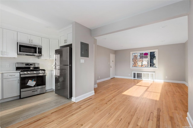 kitchen with tasteful backsplash, white cabinetry, stainless steel appliances, and light hardwood / wood-style flooring