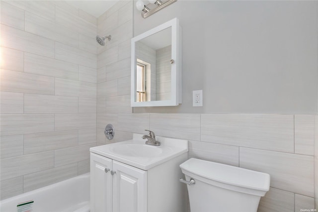 full bathroom with vanity, toilet, tile walls, and tiled shower / bath combo