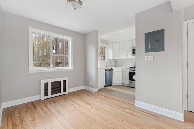 interior space with electric panel, sink, and light hardwood / wood-style floors