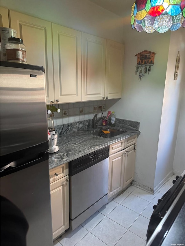 kitchen featuring light tile patterned flooring, dark stone countertops, sink, and appliances with stainless steel finishes