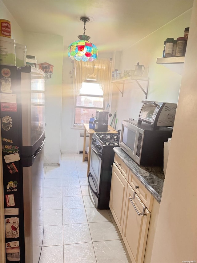 kitchen with light brown cabinetry, light tile patterned floors, decorative light fixtures, range, and fridge