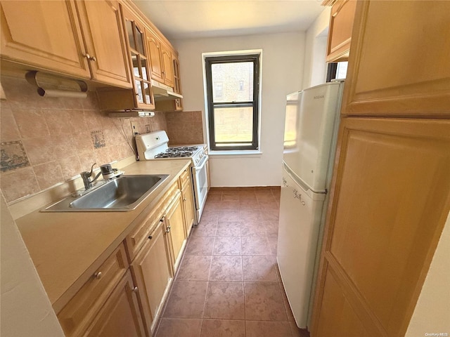 kitchen featuring white appliances, backsplash, dark tile patterned flooring, and sink