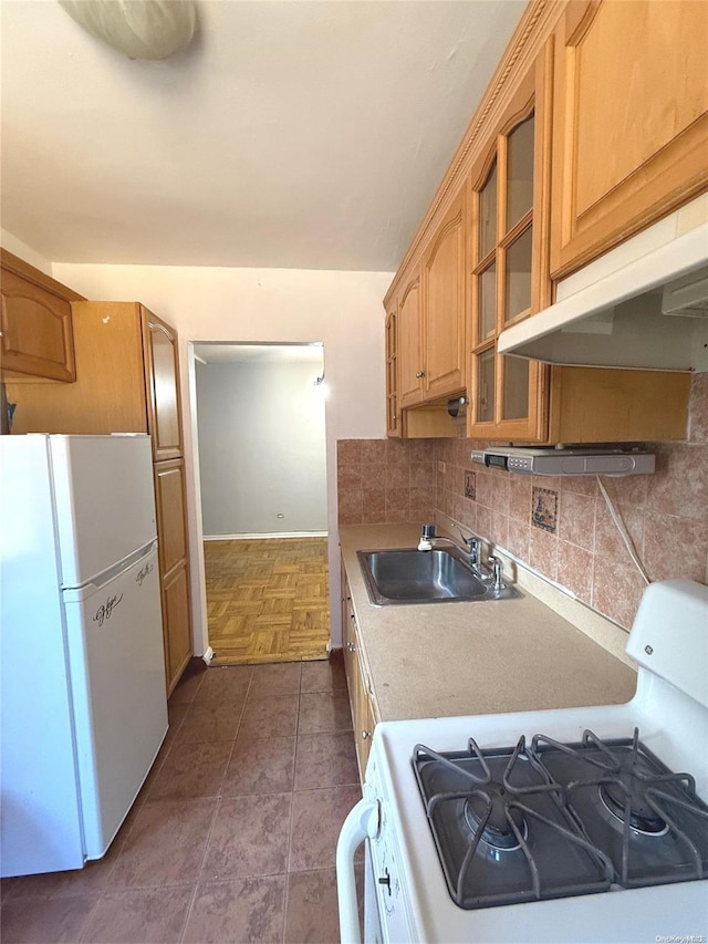 kitchen featuring decorative backsplash, white appliances, extractor fan, dark tile patterned floors, and sink