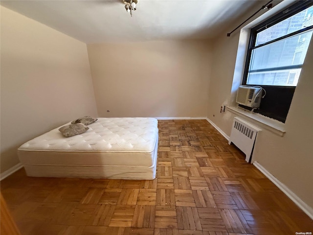 unfurnished bedroom with radiator heating unit, cooling unit, and parquet flooring