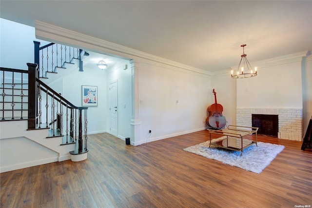 interior space featuring crown molding, a notable chandelier, dark hardwood / wood-style floors, and a brick fireplace