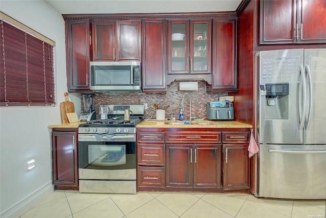 kitchen featuring decorative backsplash, sink, light tile patterned floors, and stainless steel appliances