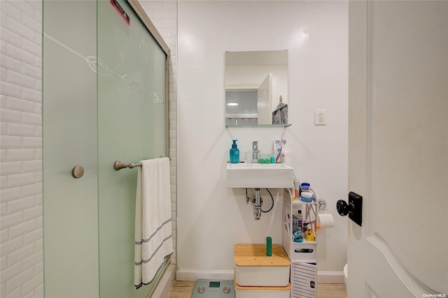 bathroom with sink, an enclosed shower, and hardwood / wood-style flooring