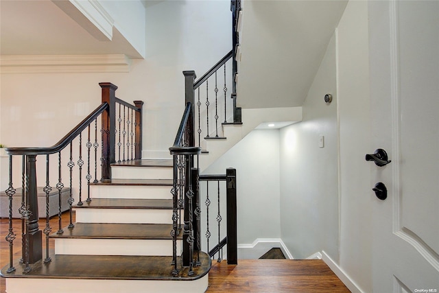 stairway featuring wood-type flooring and a high ceiling