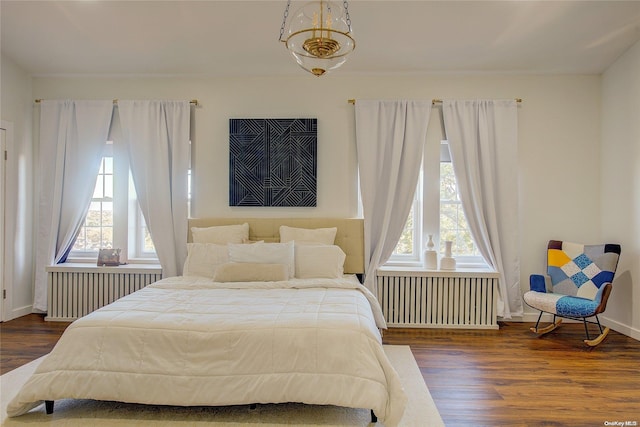 bedroom featuring radiator heating unit, multiple windows, and dark wood-type flooring