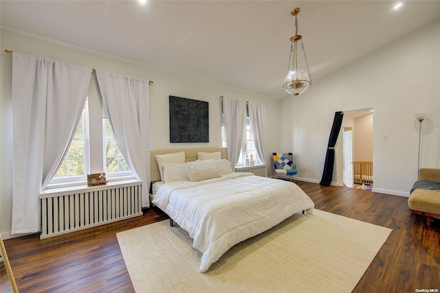 bedroom with vaulted ceiling, radiator, and dark hardwood / wood-style floors