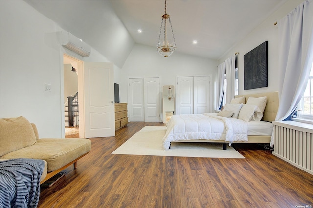 bedroom with two closets, a wall mounted AC, dark wood-type flooring, radiator heating unit, and lofted ceiling