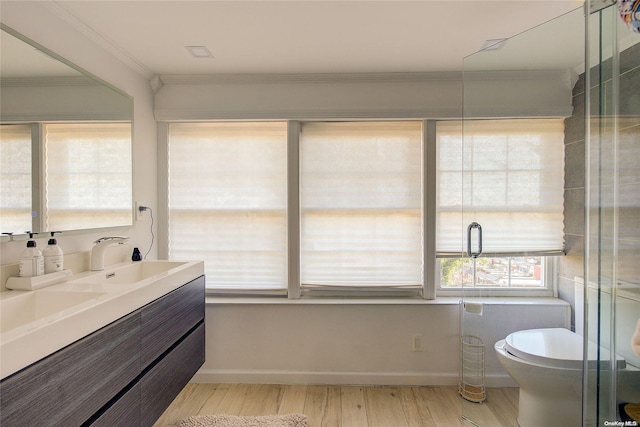 bathroom with a wealth of natural light, crown molding, wood-type flooring, and toilet