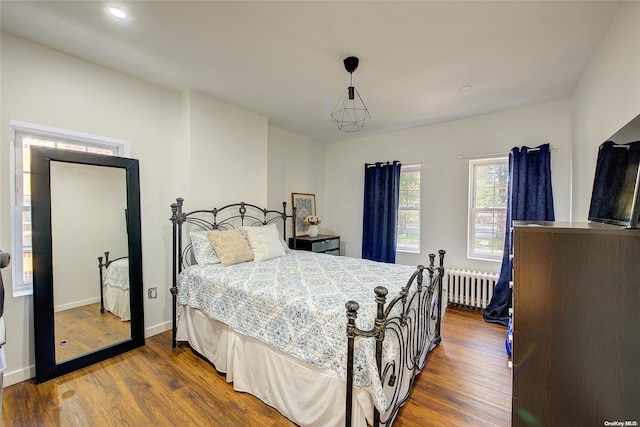 bedroom with dark hardwood / wood-style flooring and radiator